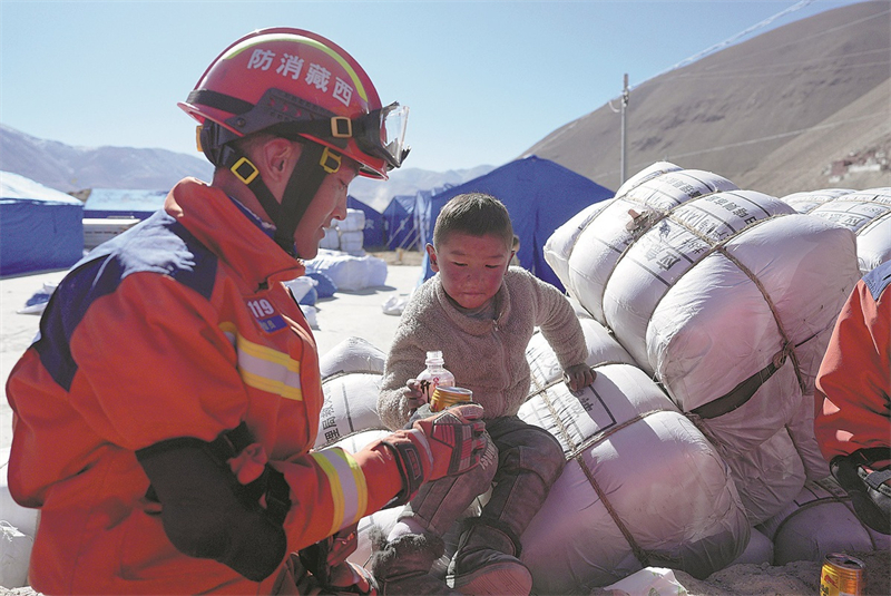 ?να μ?λο? των πυροσβεστικ?ν μον?δων αλληλοεπιδρ? με ?να απ? τα αν?λικα παιδι? τη? περιοχ?? την επ?μενη μ?ρα απ? τον μεγ?λο σεισμ?. Τετ?ρτη 8/1/2025. Φωτογραφ?α: Xinhua