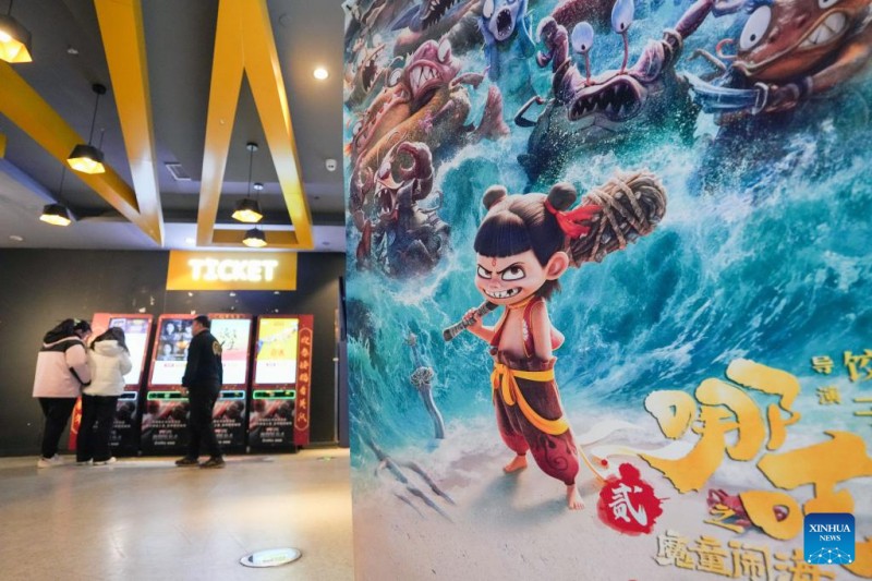 Αυτ? η φωτογραφ?α, που τραβ?χτηκε στι? 13 Φεβρουαρ?ου 2025, δε?χνει μια αφ?σα τη? κινεζικ?? ταιν?α? κινουμ?νων σχεδ?ων "Ne Zha 2" σε ?ναν κινηματογρ?φο στην περιοχ? Τσαογι?νγκ του Πεκ?νου, πρωτε?ουσα? τη? Κ?να?. Με συνολικ? παγκ?σμια ?σοδα ?νω των 10 δισεκατομμυρ?ων γιου?ν (περ?που 1,39 δισεκατομμ?ρια δολ?ρια ΗΠΑ), συμπεριλαμβανομ?νων των προπωλ?σεων, το "Ne Zha 2" ε?ναι η πρ?τη ταιν?α που ξεπερν? το 1 δισεκατομμ?ριο δολ?ρια σε μ?α μ?νο αγορ? και η πρ?τη μη χολιγουντιαν? παραγωγ? που εντ?σσεται στο πολυπ?θητο ?κλαμπ του δισεκατομμυρ?ου?. Με τι? εγχ?ριε? εισπρ?ξει? να αναμ?νεται να ξεπερ?σουν τα 15 δισεκατομμ?ρια γιου?ν, η ταιν?α ε?ναι ?τοιμη να γ?νει η πιο επιτυχημ?νη ταιν?α κινουμ?νων σχεδ?ων ?λων των εποχ?ν και μ?α απ? τι? π?ντε κορυφα?ε? εμπορικ? επιτυχημ?νε? ταιν?ε? παγκοσμ?ω?.