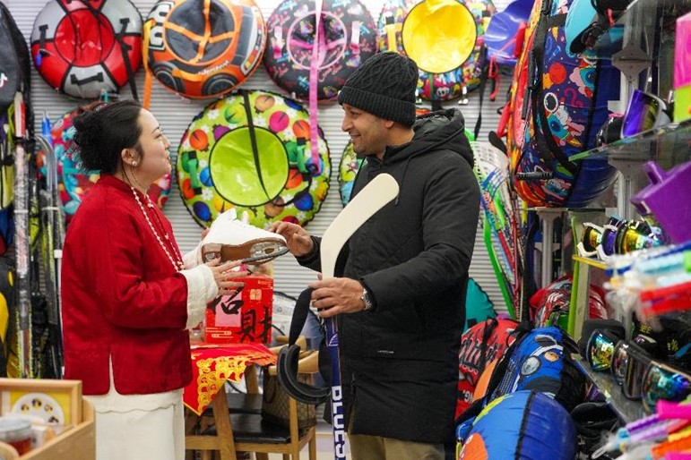 ?να? ξ?νο? ?μπορο? διαπραγματε?εται με ?ναν Κιν?ζο πωλητ? για μια συμφων?α αγορ?? χειμερινο? αθλητικο? εξοπλισμο? στην Διεθν? Αγορ? Εμπορ?ου του Γιγο? (Yiwu International Trade Market), στην π?λη Γιγο?, στην επαρχ?α Τζετζι?νγκ τη? ανατολικ?? Κ?να?, στι? 9 Φεβρουαρ?ου 2025. (Φωτογραφ?α: Zhang Yongtao/People's Daily Online)