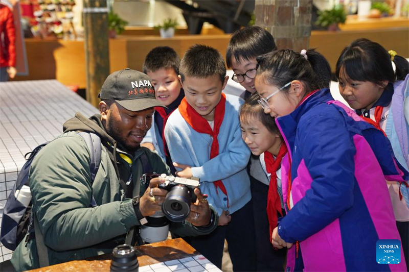 Ο Jerald Devin Braddock Jr δε?χνει φωτογραφ?ε? σε μαθητ?? στο Περ?πτερο Επ?δειξη? Τεχνουργημ?των του Hangzhou, στην επαρχ?α Zhejiang τη? ανατολικ?? Κ?να?, 28 Μαρτ?ου 2025. (Φωτογραφ?α / Xinhua)