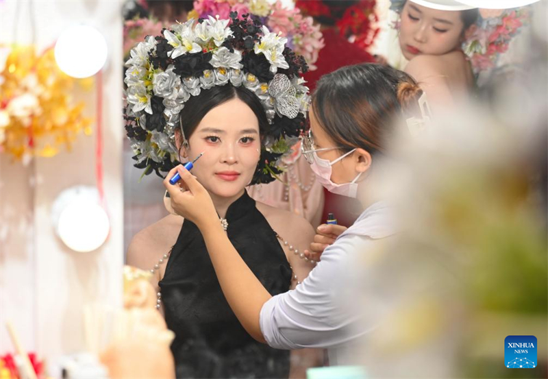 Τουρ?στρια που φορ?ει ?να λουλουδ?το στεφ?νι κεφαλιο? κ?νει το μακιγι?ζ τη? σε ?να στο?ντιο ταξιδιωτικ?? φωτογραφ?α? στο χωρι? Σουνπο?, στην π?λη Τσουαντζ?ου τη? επαρχ?α? Φουτζι?ν, στι? 18 Αυγο?στου του 2025. (Φωτογραφ?α / Xinhua)